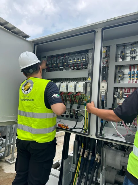 Technicians inspecting the electrical control panel of a chiller system